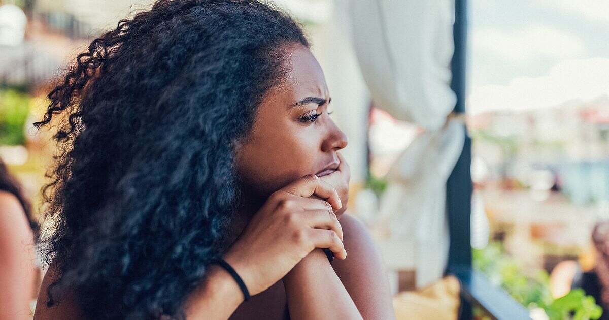 Black woman looking out window in thought